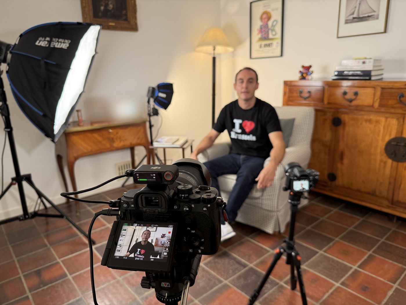 Tournage vidéo chez un client : caméra avec micro sans fil au premier plan, seconde caméra et softbox autour de l'invité