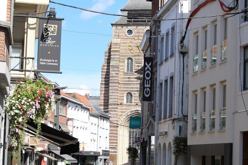 Rue commerçante du centre-ville de Wavre, avec la tour de l'église Saint-Jean-Baptiste en arrière-plan
